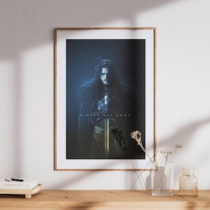 Pode incluir: Pôster emoldurado com um personagem de uma série de fantasia, segurando uma espada. A imagem tem um fundo escuro, azulado com o texto "WINTER HAS COME". O pôster é exibido em uma superfície de madeira.