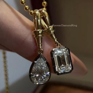 Peut inclure: Un collier en or avec deux pendentifs en diamant. L'un est en forme de poire, l'autre est de taille émeraude. Les diamants sont sertis dans des lunettes noires et suspendus à une chaîne en or.