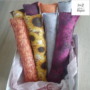 May include: A collection of colorful, rectangular fabric items in a white box. The fabrics feature patterns like sunflowers, swirls, and abstract designs in shades of orange, purple, and pink. The text "Just Sew Right!" is in the upper right corner.