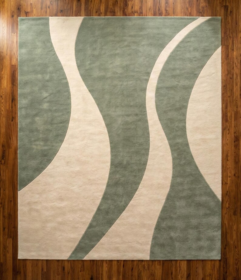May include: A rectangular area rug with a flowing design. The rug features a light green background with three off-white, wavy stripes. The rug is placed on a wooden floor.