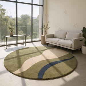 Op de afbeelding: Een ronde vloerkleed met een golvend patroon in groen, beige en blauw. Het kleed ligt in een moderne woonkamer met een bank, bijzettafel en grote ramen. De diameter van het kleed is ongeveer 250 cm.
