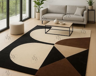 May include: A contemporary rug with a geometric pattern in black, beige, and brown. The rug's design includes large, rounded shapes and triangular sections, enhancing the modern living room. It's placed on a light wooden floor, adding warmth to the space.