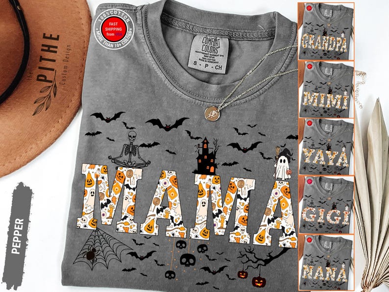 May include: A gray Comfort Colors t-shirt with a Halloween theme, featuring the word "MAMA" in a patterned font with pumpkins and candy. The shirt has bats, a skeleton, and a haunted house design. Additional shirts with "GRANDPA", "MIMI", "YAYA", "GIGI", and "NANA" are also shown.