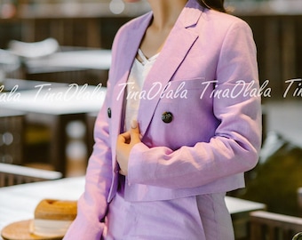 Può includere: Un completo in lino lilla chiaro, composto da un blazer corto con bottoni a doppio petto e pantaloni abbinati. Il completo è indossato sopra un top bianco. L'immagine include il testo "TinaOlala" sullo sfondo.
