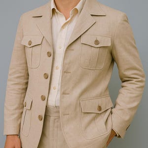 Puede incluir: Un traje de lino beige, con una chaqueta con cuatro bolsillos delanteros y pantalones a juego. La chaqueta tiene solapas con muescas y botones. El traje es de color neutro, adecuado para diversas ocasiones.