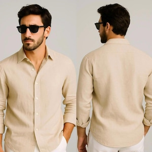 Può includere: Camicia beige chiaro a maniche lunghe con bottoni. La camicia ha un colletto classico ed è realizzata in un tessuto leggero. Le maniche sono arrotolate. Il modello indossa occhiali da sole neri e pantaloni bianchi. La camicia è mostrata davanti e dietro.