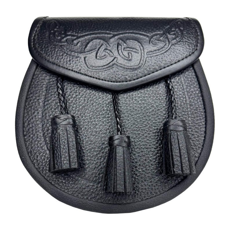 May include: Black leather sporran with a Celtic knot design on the flap. The sporran has three black tassels hanging from the bottom. The pouch is oval-shaped and has a textured surface.
