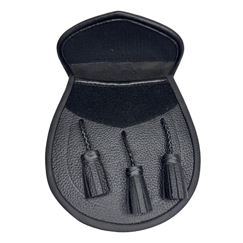 May include: Black leather sporran with three decorative tassels. The sporran has a textured front and a flap closure. The top of the sporran is a smooth black material.