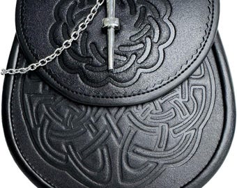 May include: Black leather sporran with embossed Celtic knot designs. The sporran features a flap closure with a decorative metal pin and chain. The pouch is a traditional Scottish accessory.