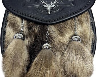 May include: A black leather sporran with a silver stag emblem and Celtic knotwork. The front features a fur panel with three decorative tassels hanging from silver chains. A traditional Scottish accessory.