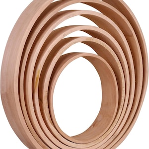 May include: A set of unfinished wooden rings, nested within each other to create a layered circular design. The natural wood grain is visible, showcasing the material's texture and color. The rings vary in size, forming a three-dimensional shape.