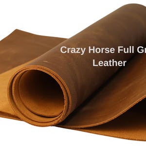 May include: Close-up of Crazy Horse Full Grain Leather in shades of brown. The leather is rolled and folded, showcasing its texture and color variations. The text "Crazy Horse Full Grain Leather" is visible.