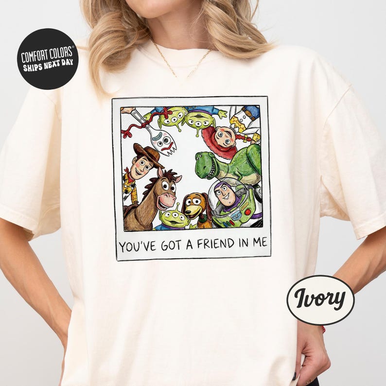 A person wearing a white t-shirt with a graphic design featuring characters from the Toy Story movie, including Woody, Buzz Lightyear, and other beloved characters.