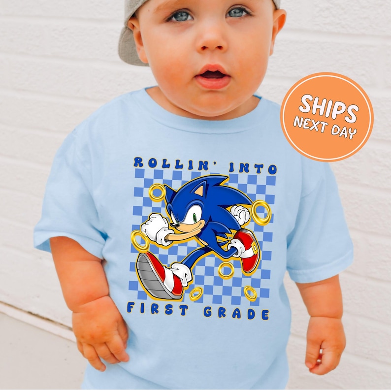 A baby wearing a blue t-shirt with a graphic of Sonic the Hedgehog and the text "Rollin' into first grade" printed on it.