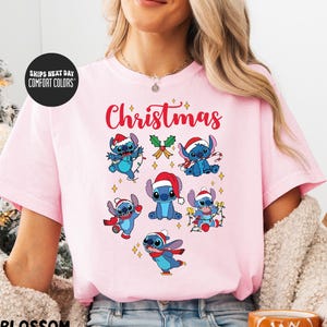 A woman wearing a pink t-shirt with a Christmas-themed design featuring various cartoon characters.