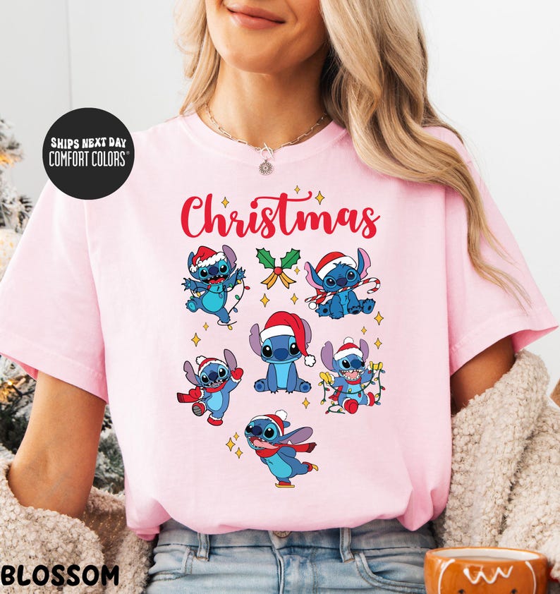 A woman wearing a pink t-shirt with a Christmas-themed design featuring various cartoon characters.