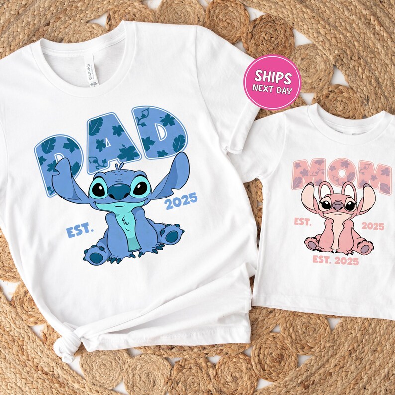two white t-shirts with a design of a blue cartoon character, likely a character from the popular animated series "Stitch". The t-shirts are labeled with the text "PAD" and "MOM", indicating they are intended for a father and mother. The t-shirts are displayed on a woven mat, and there is a pink shipping label in the top right corner, suggesting that the t-shirts are being shipped.