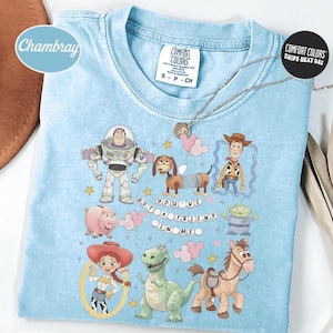 A blue t-shirt with various cartoon characters from the Toy Story franchise, including Buzz Lightyear, Woody, and other beloved characters, along with a message that says "You've got a friend in me".