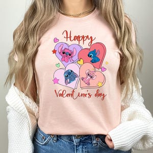 A woman wearing a pink t-shirt with a graphic design featuring characters from the Disney animated film "Stitch" and the text "Happy Valentine's day".
