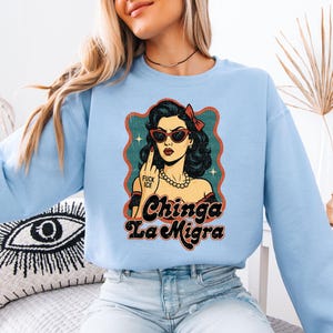 a woman wearing a blue sweatshirt with a picture of a woman wearing sunglasses
