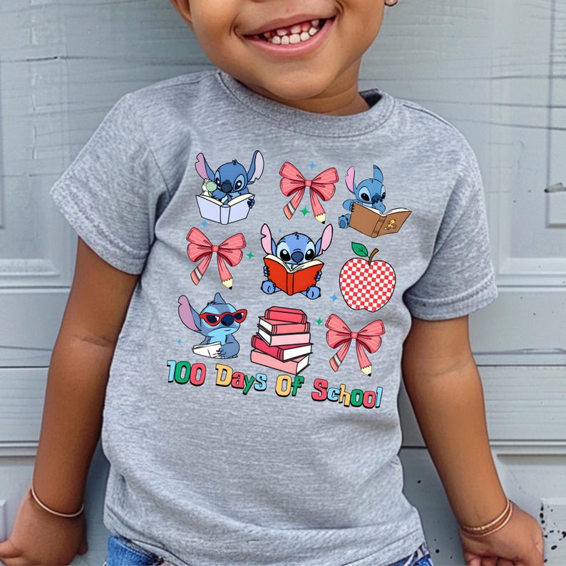 A young child wearing a gray t-shirt with a graphic design featuring various cartoon characters and school-related items, such as books, apples, and pencils.