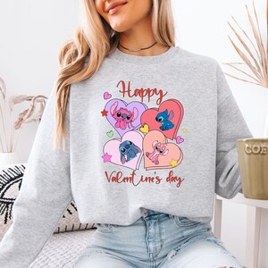 A woman wearing a gray sweatshirt with a graphic design featuring cartoon characters and the text "Happy Valentine's day".