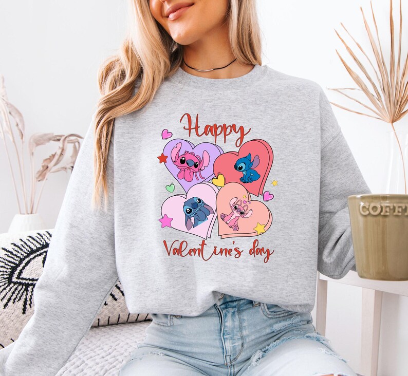 A woman wearing a gray sweatshirt with a graphic design featuring cartoon characters and the text "Happy Valentine's day".