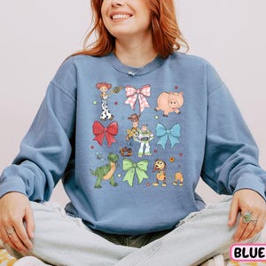 a woman sitting on a bed wearing a blue sweatshirt