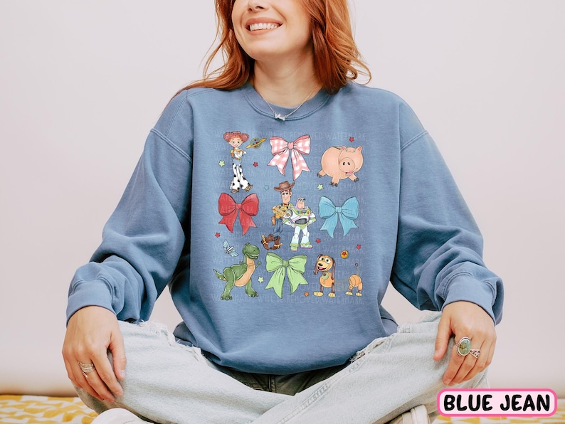 a woman sitting on a bed wearing a blue sweatshirt