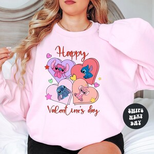 A woman wearing a pink sweatshirt with a graphic design featuring characters from the Disney animated film "Stitch".