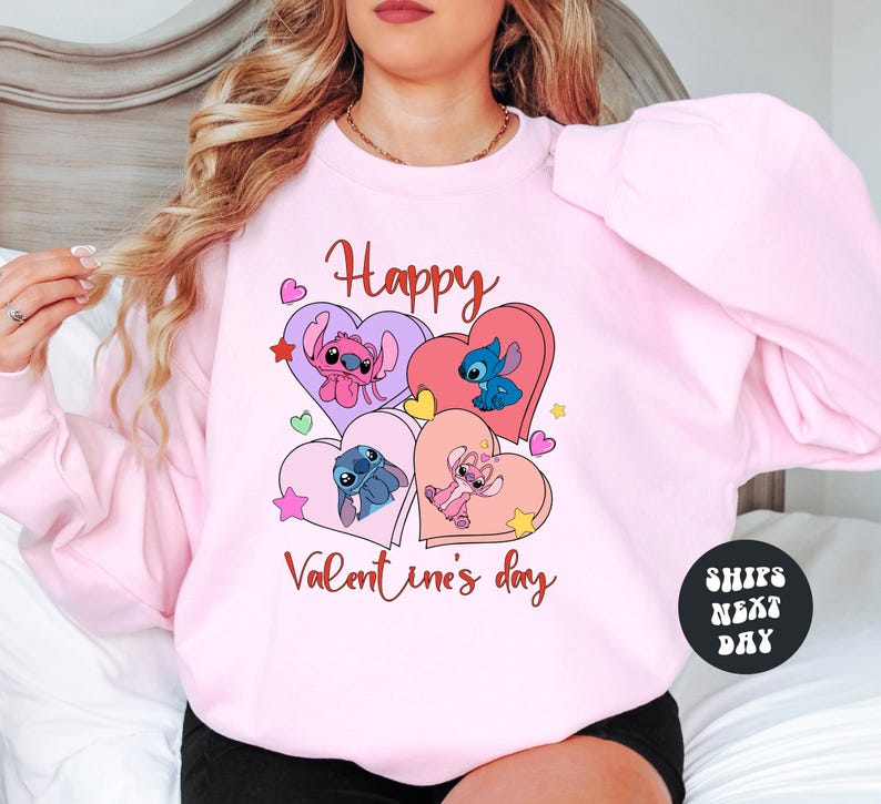 A woman wearing a pink sweatshirt with a graphic design featuring characters from the Disney animated film "Stitch".
