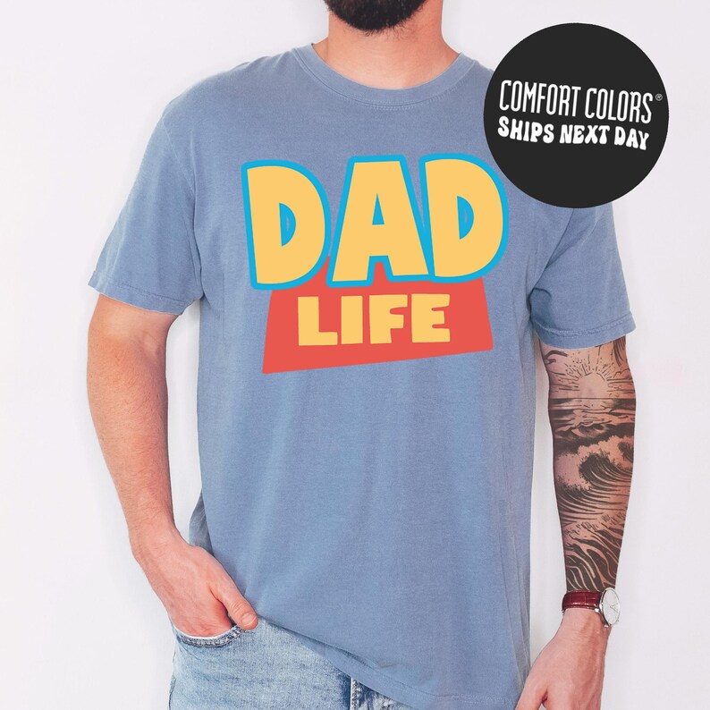 A man wearing a blue t-shirt with the text "DAD LIFE" printed on it.