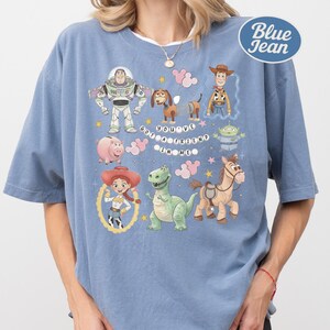 A person wearing a blue t-shirt with various cartoon characters and a message printed on it.