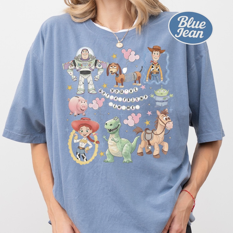 A person wearing a blue t-shirt with various cartoon characters and a message printed on it.