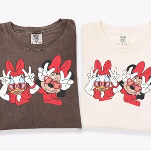 two t-shirts with cartoon Minnie Mouse characters printed on them.