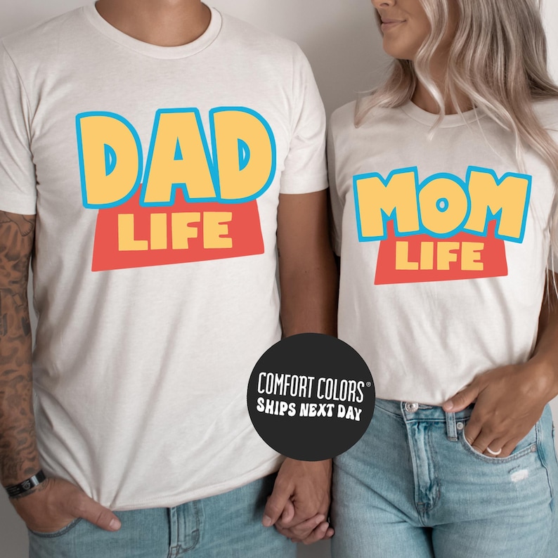 A man and a woman wearing matching t-shirts with the text "DAD LIFE" and "MOM LIFE" printed on them.