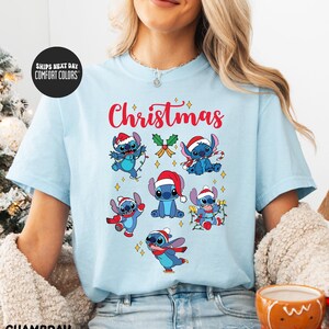 A woman wearing a light blue t-shirt with a Christmas-themed design featuring various cartoon characters.