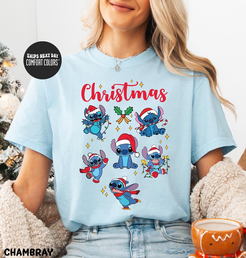 A woman wearing a light blue t-shirt with a Christmas-themed design featuring various cartoon characters.