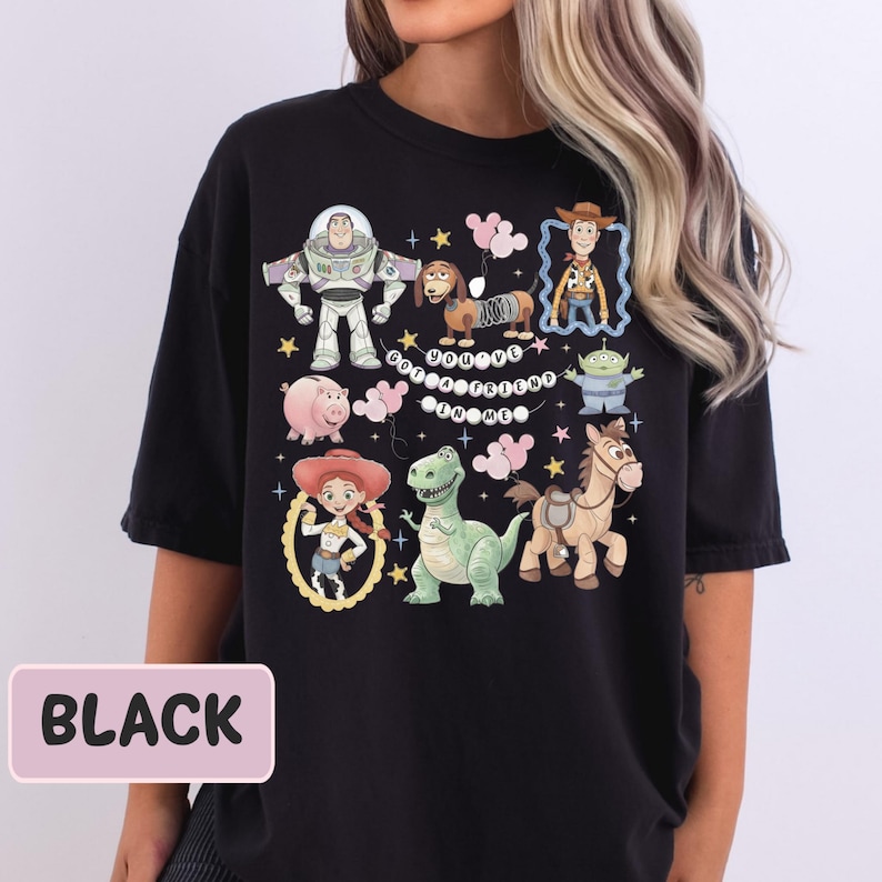 A black t-shirt with a colorful graphic design featuring characters from the Toy Story movie franchise, including Buzz Lightyear, Woody, and other beloved characters.