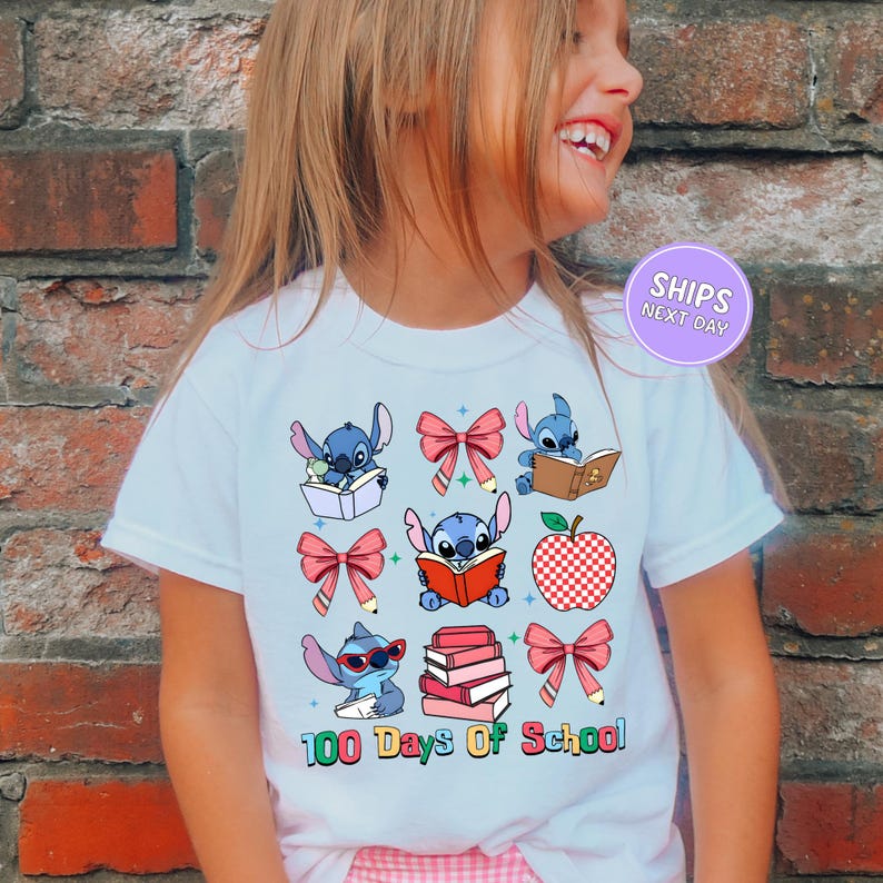 A young girl wearing a white t-shirt with a graphic design featuring various cartoon characters and text related to school.