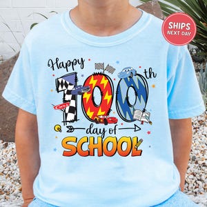 A person wearing a light blue t-shirt with a graphic design celebrating the 100th day of school.