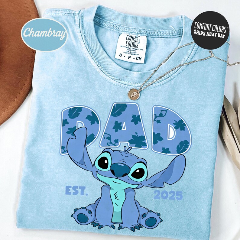 A blue t-shirt with a cartoon character and text printed on it, along with a necklace and a tag.