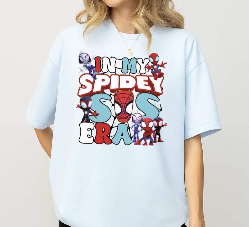 A person wearing a white t-shirt with a graphic design featuring various Spider-Man characters and text.