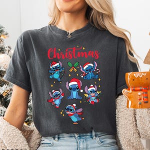 A woman wearing a gray t-shirt with a Christmas-themed design featuring various cartoon characters.