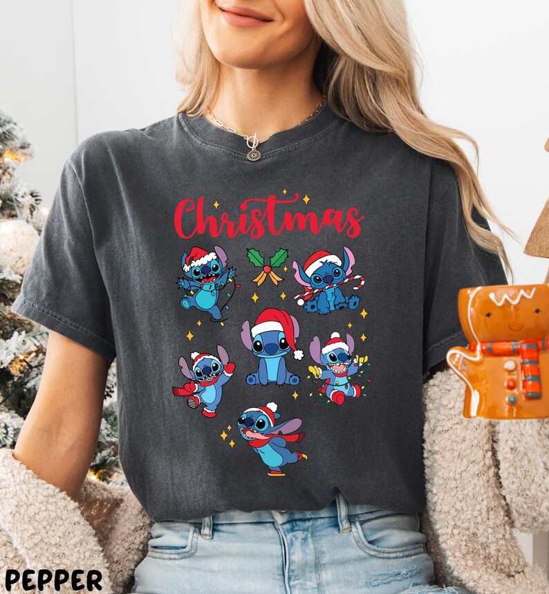 A woman wearing a gray t-shirt with a Christmas-themed design featuring various cartoon characters.