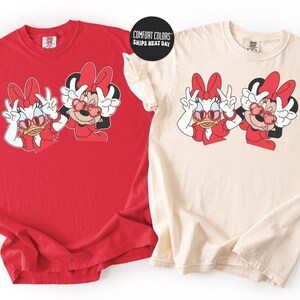 two t-shirts with the same cartoon character design, Minnie Mouse, wearing sunglasses and posing with her friends.