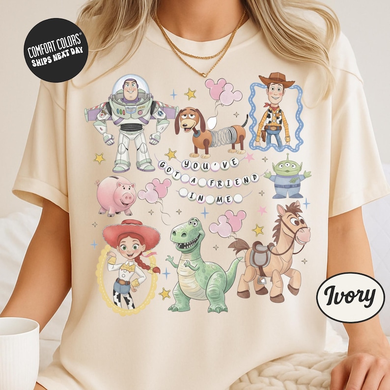 a person wearing a white t-shirt with a collage of various cartoon characters from the Toy Story franchise, including Buzz Lightyear, Woody, and other beloved characters.