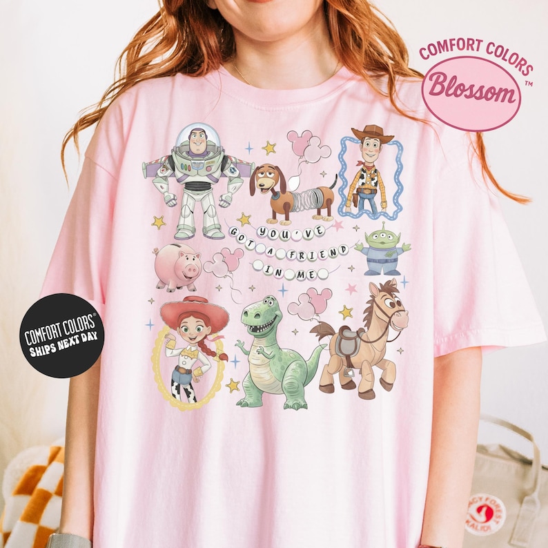 A person wearing a pink t-shirt with various cartoon characters and a message printed on it.