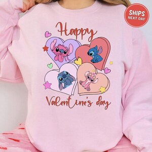 A pink sweatshirt with a graphic design featuring characters from the Disney animated film "Stitch". The design includes hearts, stars, and the text "Happy Valentine's day".