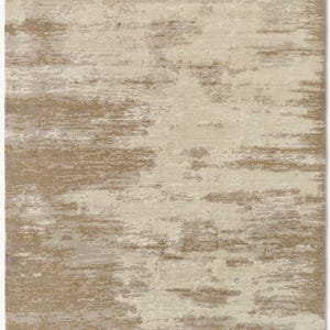May include: A rectangular area rug featuring an abstract, distressed pattern in shades of beige, cream, and light brown. The design consists of horizontal, textured streaks and mottled patches that create a layered, weathered appearance across the surface.